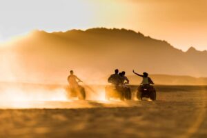 Three individuals riding RTVs